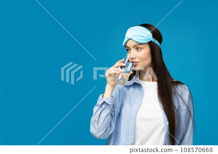 A young woman in a sleeping mask and a glass of water A young woman in a sleeping mask and a glass of water 108570668