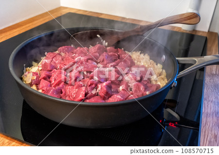 sliced onions and meat are frying in a pan sliced onions and meat are frying in a pan 108570715
