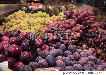 Grapes and plums on counter in supermarket, close up 108570773