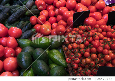 Tomatoes, cucumbers and avocados in wicker baskets in supermarket 108570778