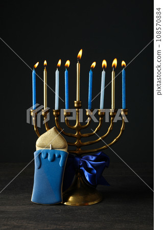 Hanukkiah with ribbon and gingerbread on black background Hanukkiah with ribbon and gingerbread on black background 108570884