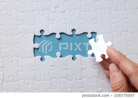 White puzzles and hand on blue background, top view 108570897