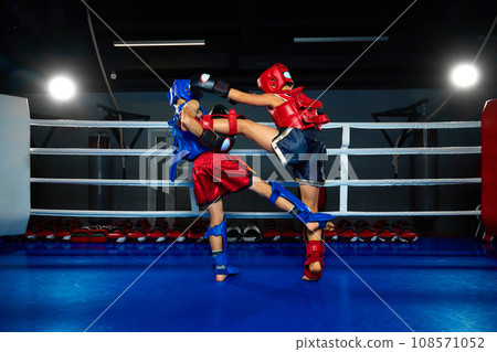 Children, martial fighter exercising kickboxing with sparring partner, fighting in ring at gym. Young professional sportsmen. 108571052