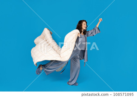 A girl with a pillow on a blue background. A girl with a pillow on a blue background. 108571095