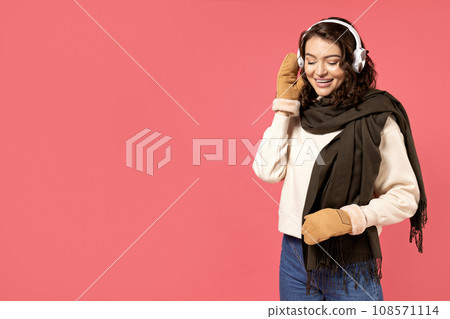 Beautiful girl in warm, winter clothes on a pink background. 108571114