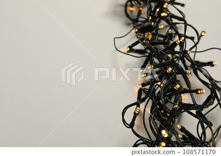 Black garland with yellow lights on gray background, space for text 108571170
