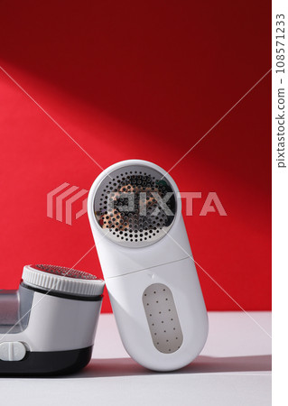 A machine for shaving fabric on clothes, on a red background. A machine for shaving fabric on clothes, on a red background. 108571233