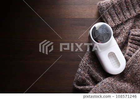 Machine for shaving fabric on clothes, on a dark background. Machine for shaving fabric on clothes, on a dark background. 108571246