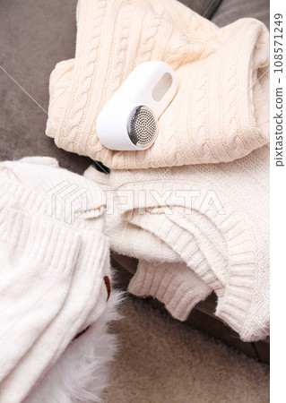 A machine for shaving fabric on clothes with sweaters nearby. A machine for shaving fabric on clothes with sweaters nearby. 108571249