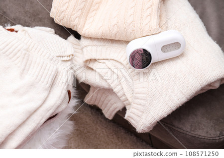 A machine for shaving fabric on clothes with sweaters nearby. A machine for shaving fabric on clothes with sweaters nearby. 108571250
