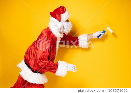 Santa Claus makes repairs on a yellow background. Santa Claus makes repairs on a yellow background. 108571621