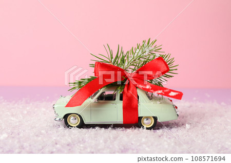 A green car with a Christmas tree and a red bow. A green car with a Christmas tree and a red bow. 108571694