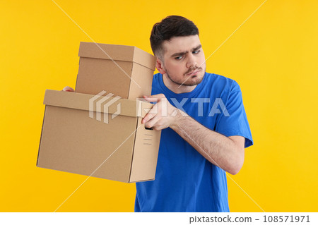 Young attractive guy with cardboard boxes in hands Young attractive guy with cardboard boxes in hands 108571971