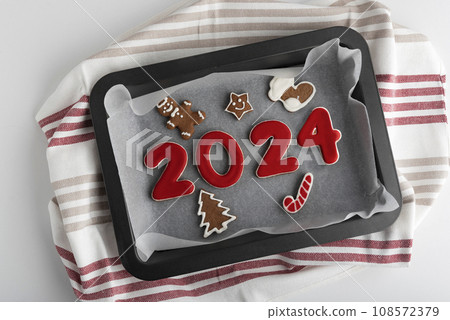 Red glazed painted cookies with numbers 2024 on light wooden background. Copy space, mockup 108572379