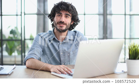 Adult businessman working in well-lit office using laptop for creative collaboration. Adult businessman working in well-lit office using laptop for creative collaboration. 108572520