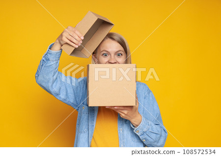 An attractive blonde looks into a cardboard box An attractive blonde looks into a cardboard box 108572534