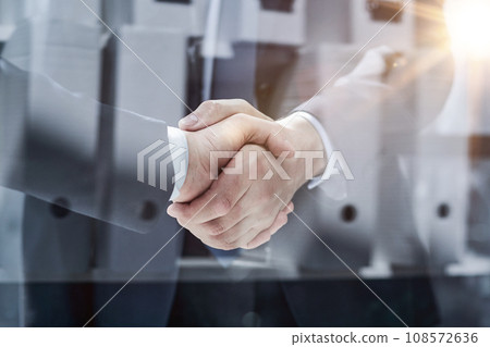 executives shaking hands in front of their manager and a colleague executives shaking hands in front of their manager and a colleague 108572636