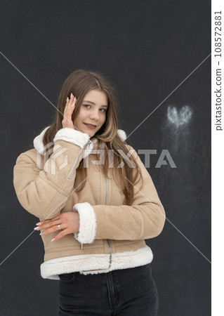 Smiling pretty girl in fashionable beige sheepskin coat, studio black background. Fashionable outerwear. Vertical frame Smiling pretty girl in fashionable beige sheepskin coat, studio black background. Fashionable outerwear. Vertical frame 108572881