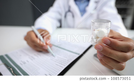 The doctor writes a prescription holding pills in his hand 108573051