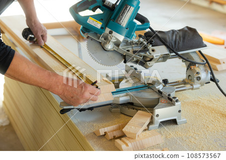 Carpenter using power tools to cut wood 108573567