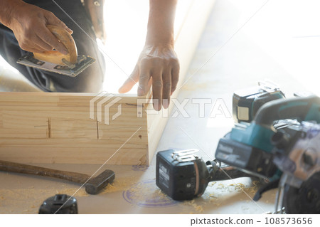 A man who works as a carpenter using wood 108573656