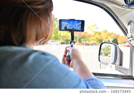 一位女士在車內用智慧型手機拍照,直播秋葉 一位女士在車內用智慧型手機拍照,直播秋葉 108573845