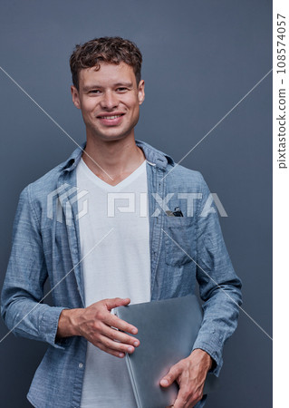 young man on a gray background holding a laptop young man on a gray background holding a laptop 108574057