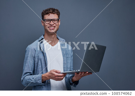 young man on a gray background holding a laptop 108574062
