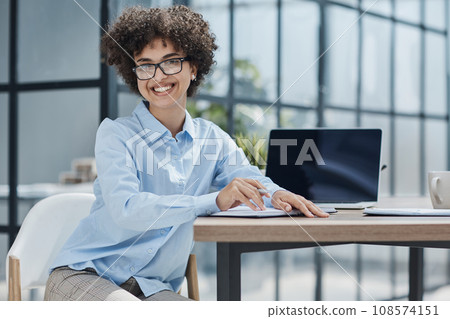 Happy female designer standing in office Happy female designer standing in office 108574151