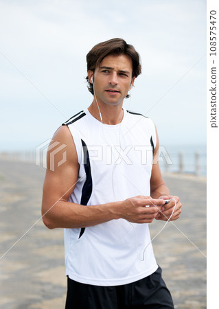 Man, fitness and earphones to listen to music, podcast and song on run, exercise and cardio. Male athlete, hearing and streaming radio, audio and sound by ocean, outdoors and inspiration for workout Man, fitness and earphones to listen to music, podcast and song on run, exercise and cardio. Male athlete, hearing and streaming radio, audio and sound by ocean, outdoors and inspiration for workout 108575470