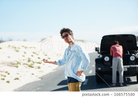 Men, car and hitchhiking in road for help or engine problem on roadtrip or journey outdoor in desert. People, travelers and transport risk in street or highway with roadside crisis and assistance Men, car and hitchhiking in road for help or engine problem on roadtrip or journey outdoor in desert. People, travelers and transport risk in street or highway with roadside crisis and assistance 108575580