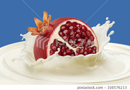 Pomegranate falling into milk splash isolated on color background 108576213
