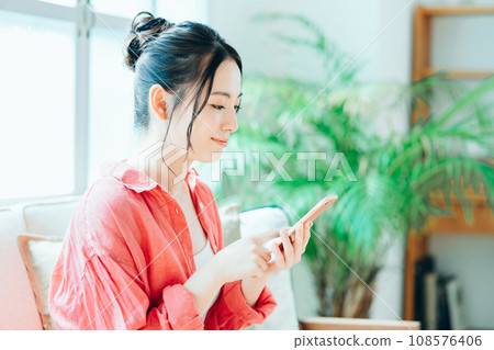 A young woman doing online shopping on her smartphone. A young woman doing online shopping on her smartphone. 108576406