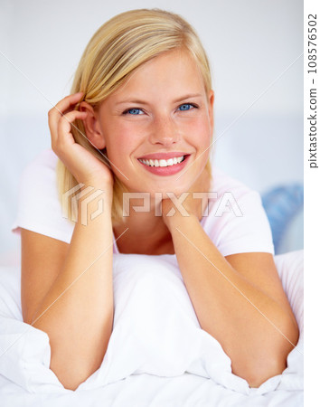 Portrait, smile and relax with a woman on her bed for the weekend to rest or chill during time off. Face, wake up and a happy young person alone in the bedroom of her home or apartment to refresh 108576502