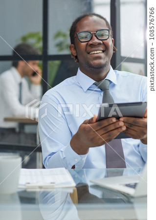 a man at a workplace at a table in front of a computer uses a tablet 108576766