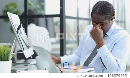 tired man works at a computer on background office. concept of trouble at work tired man works at a computer on background office. concept of trouble at work 108576835
