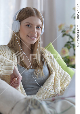 Portrait of young woman in pajamas on bed with fluffy plaid Portrait of young woman in pajamas on bed with fluffy plaid 108576876