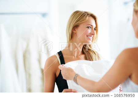 Bride, wedding dress or woman helping a customer in dressing room shopping for special day or retail. Happy, friends or sales assistant with support, fabric or clothing for marriage or fashion style 108576950