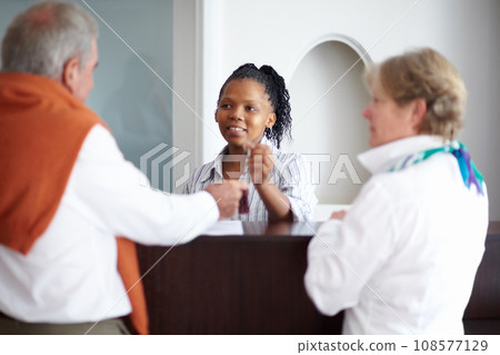 Senior couple, keys and reception at hotel for service, customer care or suite reservation at resort. Receptionist giving room access to mature man and woman for holiday, vacation or stay together 108577129