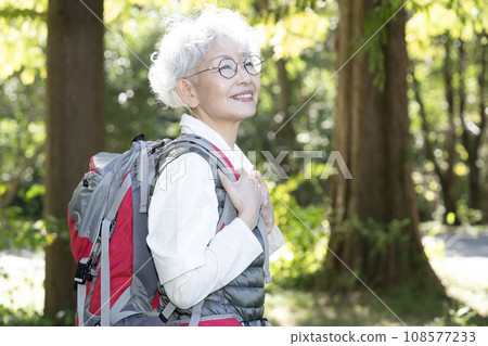 A woman hiking in the mountains carrying a mountaineering bag on her back 108577233