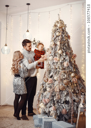 People reparing for Christmas. People playing with their daughter. Family is resting in a festive room. Child in a red dress. People reparing for Christmas. People playing with their daughter. Family is resting in a festive room. Child in a red dress. 108577418
