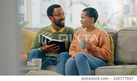 Coffee, reading and happy couple at home on a living room sofa with a man and hot drink. Book, tea and smile with communication and relax conversation together with love and support on a couch 108577687