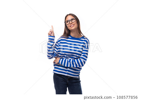 portrait of an optimistic bright european brunette young lady in a blue blouse and jeans on a white 108577856