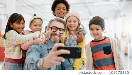 Selfie, children and teacher with smartphone, happy and smile for picture, excited and teacher. Kids, internet and cellphone for technology, online and memories for school, classroom and diversity 108578320