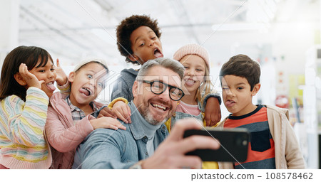 Selfie, children and teacher with funny face, smile and picture with educator, excited and happy. Kids, internet and cellphone for technology, online and memories for school, classroom or diversity 108578462