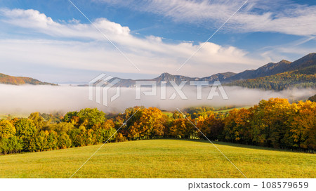 A landscape with mountain surrounded by fog in the autumn season A landscape with mountain surrounded by fog in the autumn season 108579659