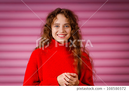 Happy smiling young adult woman wearing winter warm red sweater indoors looking at camera with joyful smile Happy smiling young adult woman wearing winter warm red sweater indoors looking at camera with joyful smile 108580372