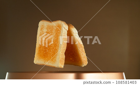 Crispy Golden Toasts Jumping out of Toaster on Bronze Gradient Background 108581403