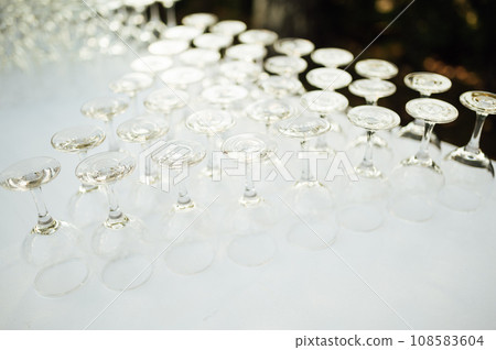 A lot of empty wine glasses. Row of clean glass transparent glasses are on a table on banquet in a bar 108583604