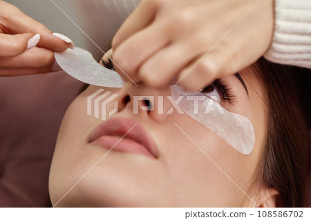 master preparing glue cotton tape under eye before eyelash extension procedure master preparing glue cotton tape under eye before eyelash extension procedure 108586702